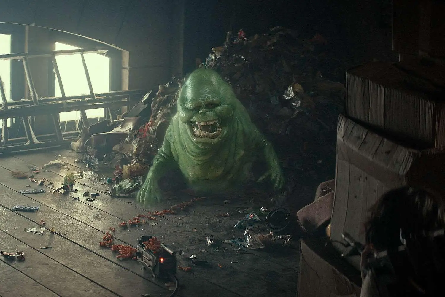Slimer, the green ghost from Ghostbusters, in a pile of junk food wrappers